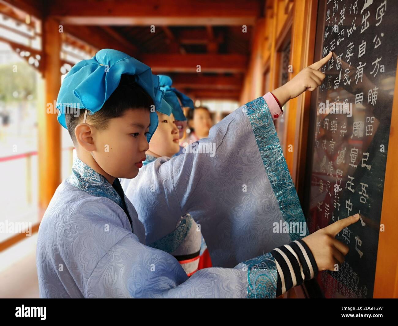 Les élèves de l'école primaire vêtus de Hanfu, un costume traditionnel chinois, écrivent la calligraphie et apprennent la culture traditionnelle dans la ville de Jilin, au nord-est Banque D'Images