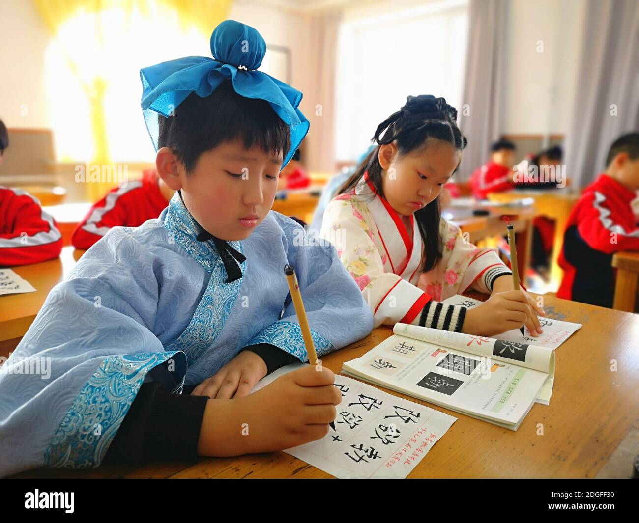 Les élèves de l'école primaire vêtus de Hanfu, un costume traditionnel chinois, écrivent la calligraphie et apprennent la culture traditionnelle dans la ville de Jilin, au nord-est Banque D'Images