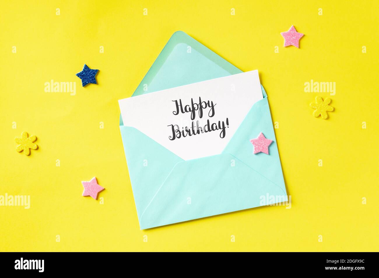 Carte De Vœux De Joyeux Anniversaire Dans Une Enveloppe Bleu Sarcelle Tire Du Haut Sur Un Fond Jaune Avec Des Etoiles Et Des Paillettes Photo Stock Alamy