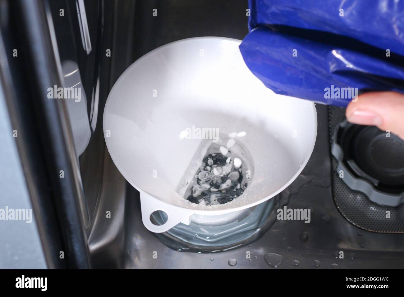 Man ouvre le réservoir de sel au lave-vaisselle et y remplit un sel spécial  Photo Stock - Alamy