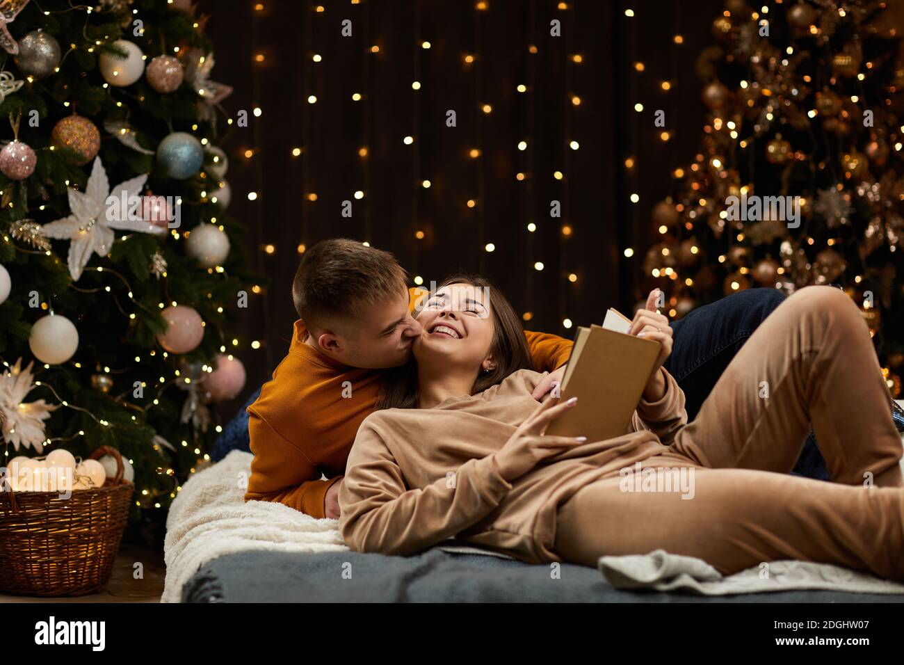 Couple amoureux fête Noël à la maison. Couple amoureux encadre et livre de  lecture près de l'arbre de Noël Photo Stock - Alamy