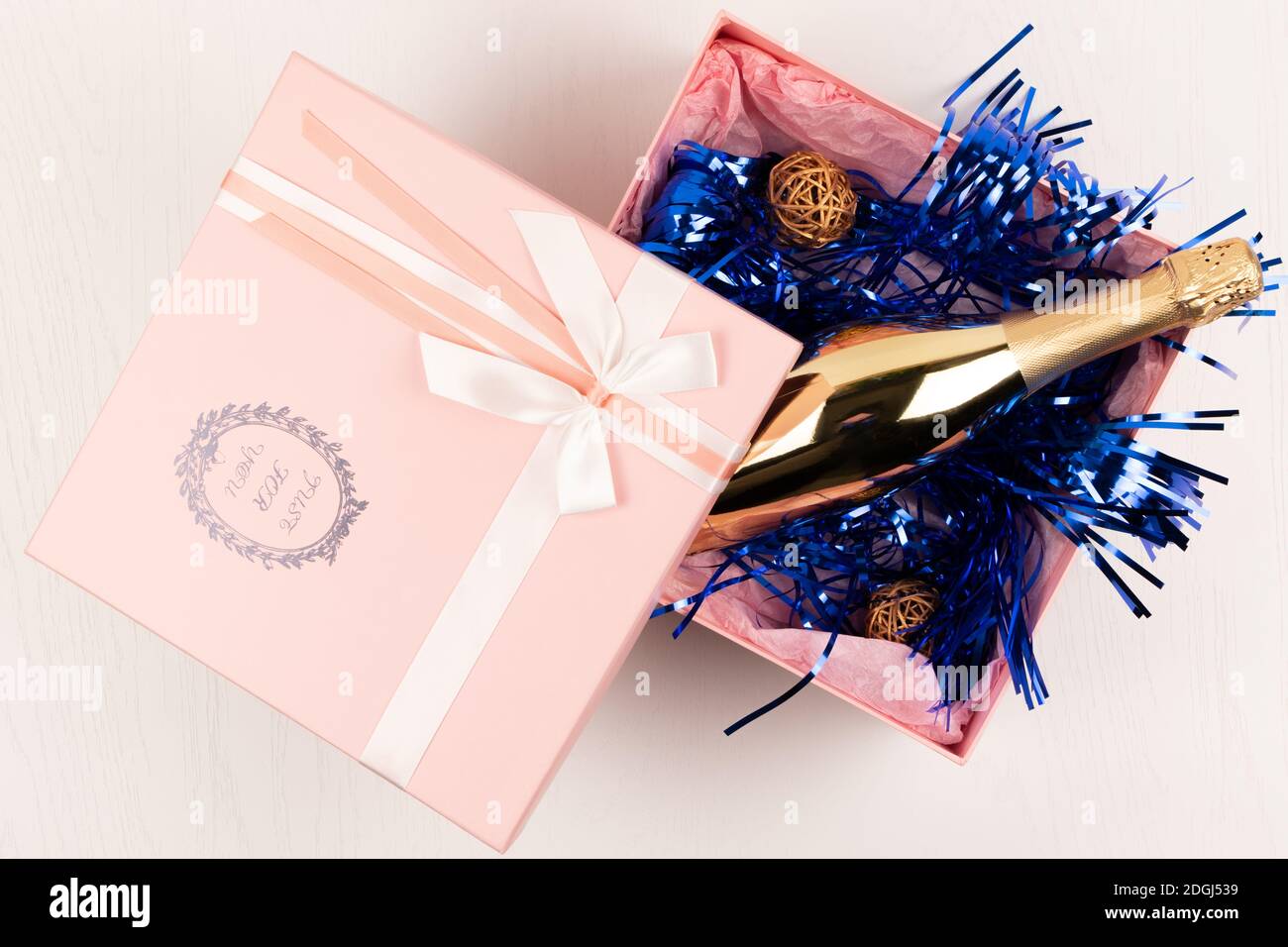 une bouteille de champagne dorée vous attend dans un cadeau rose Boîte avec  noeud et guirlande de Noël bleue sur un arrière-plan de table blanc Photo  Stock - Alamy