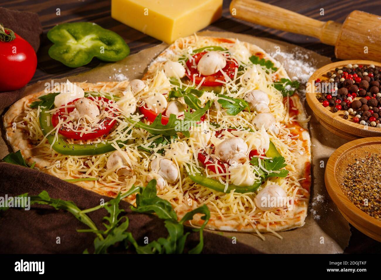 Pizza avant cuisson, légumes et épices sur fond de bois sombre Banque D'Images