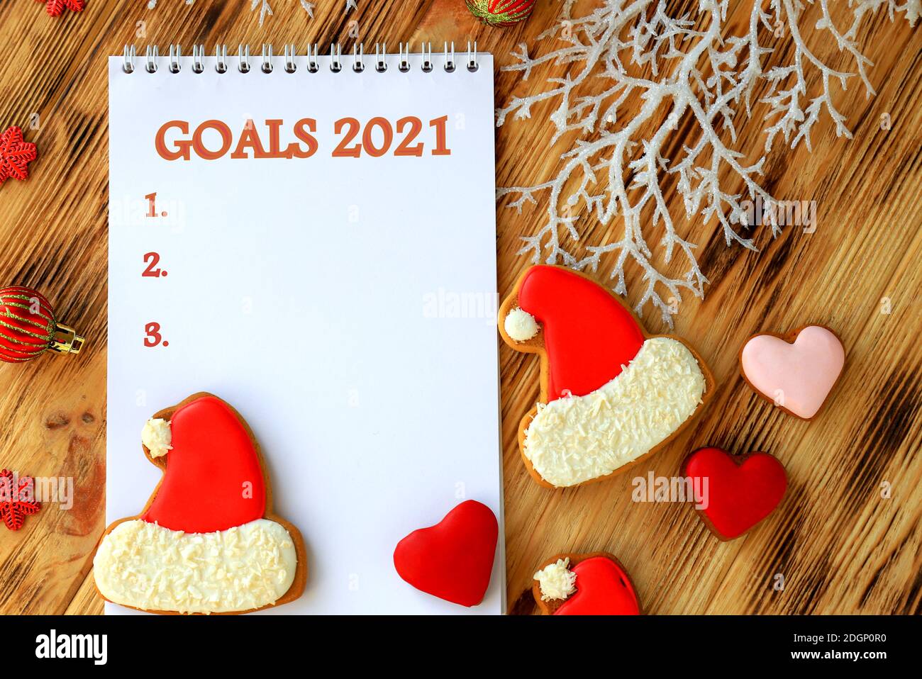 Cahier blanc pour les buts de Noël, les souhaits, les tâches pour la nouvelle année 2021 parmi les pains d'épices sous forme de chapeau de Père Noël et arbre de Noël Banque D'Images
