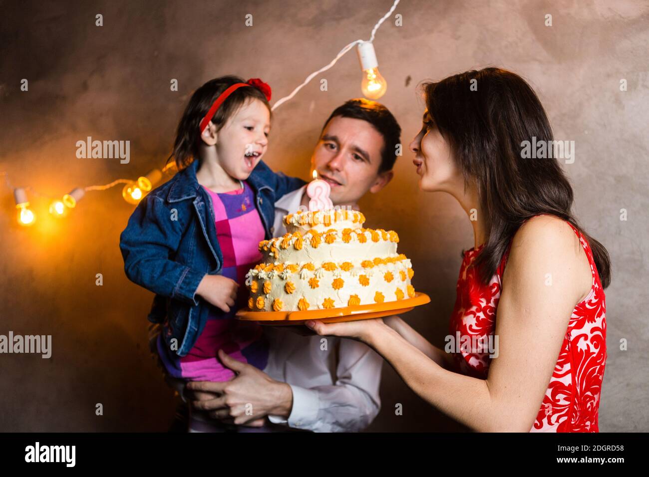 Theme Famille Vacances Enfants Anniversaire Et De Souffler Des Bougies Sur Grand Gateau Jeune Famille De Trois Personnes Debout Et Tenant Photo Stock Alamy