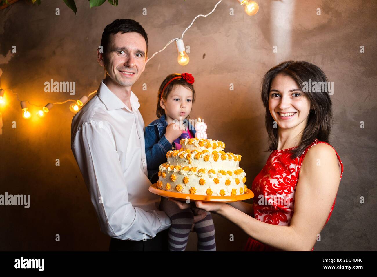 Theme Famille Vacances Enfants Anniversaire Et De Souffler Des Bougies Sur Grand Gateau Jeune Famille De Trois Personnes Debout Et Tenant Photo Stock Alamy