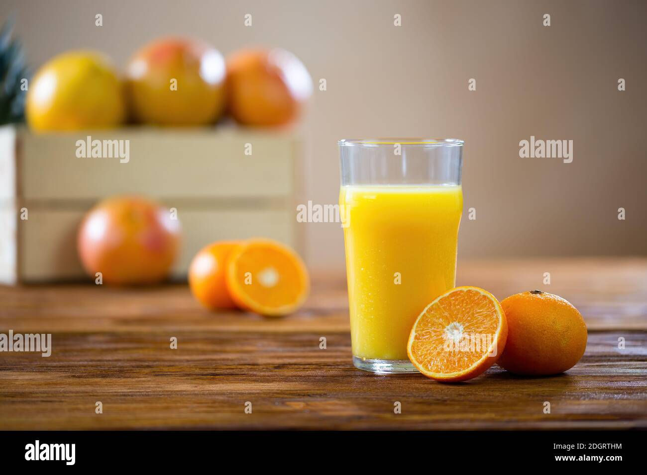 Coupe orange en deux sur une table en bois au verre de jus pressé Banque D'Images