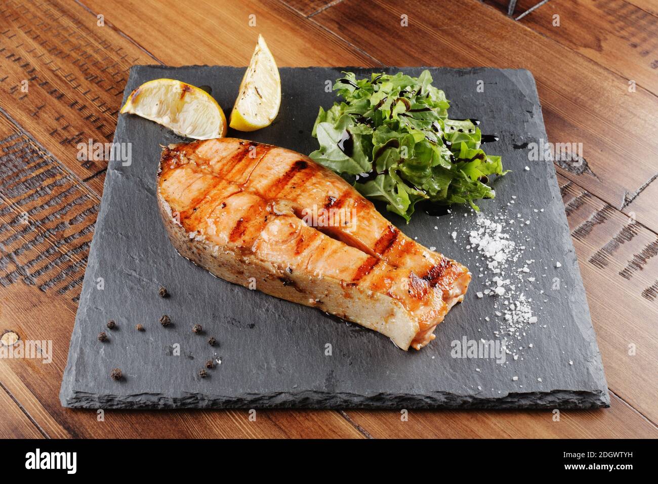 Steak de saumon au citron et vert sur une surface en ardoise. fond en bois Banque D'Images