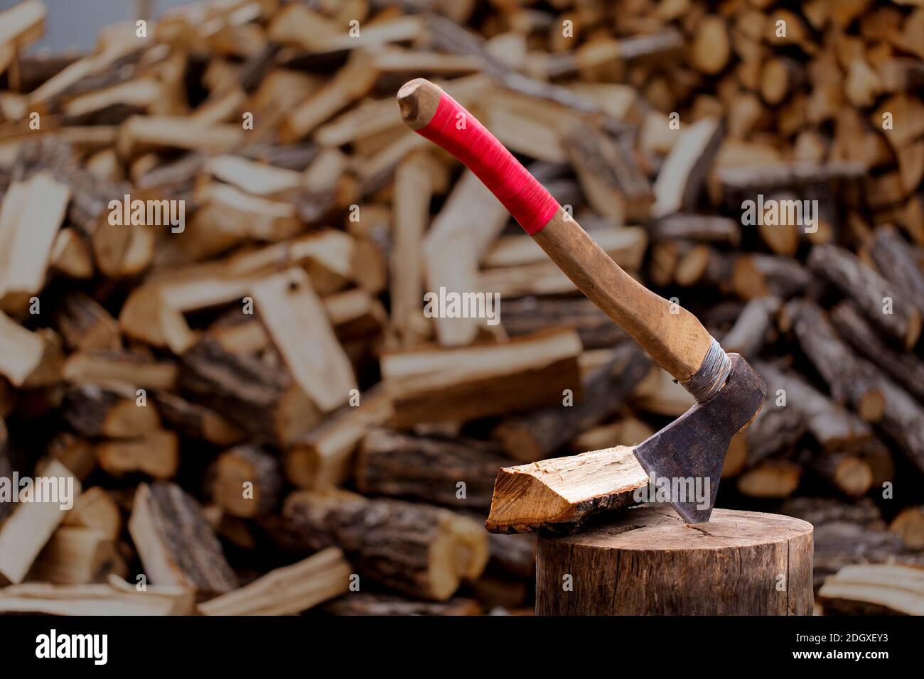 Une vieille hache en bois insérée dans un morceau de bois scié, vieux morceau de bois sur le fond de bois de chauffage haché. Banque D'Images