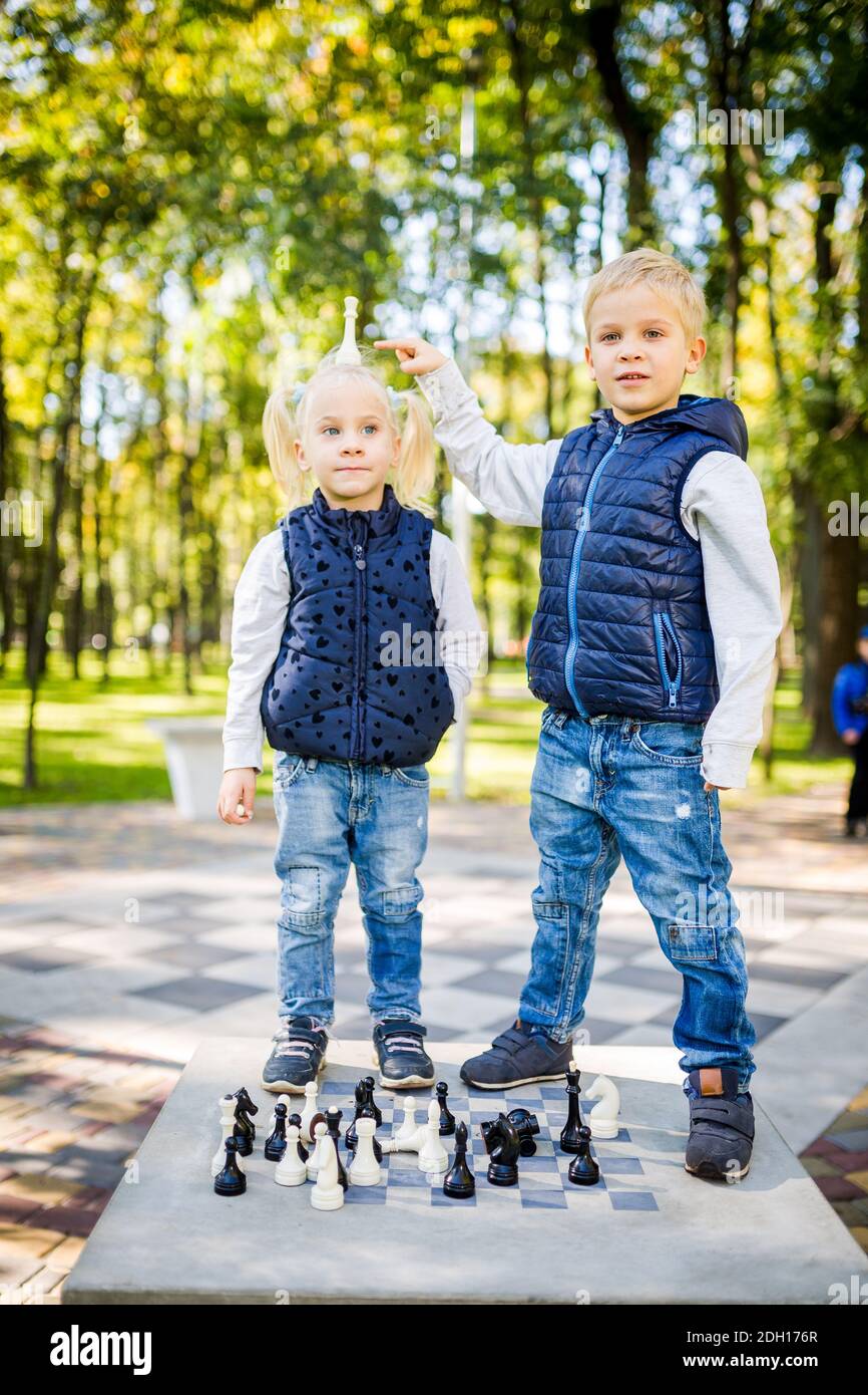 Passe-temps des enfants, des garçons et des filles jouant aux échecs. Drôle petit frère et soeur jouant des échecs en plein air dans le parc sur une place publique Banque D'Images