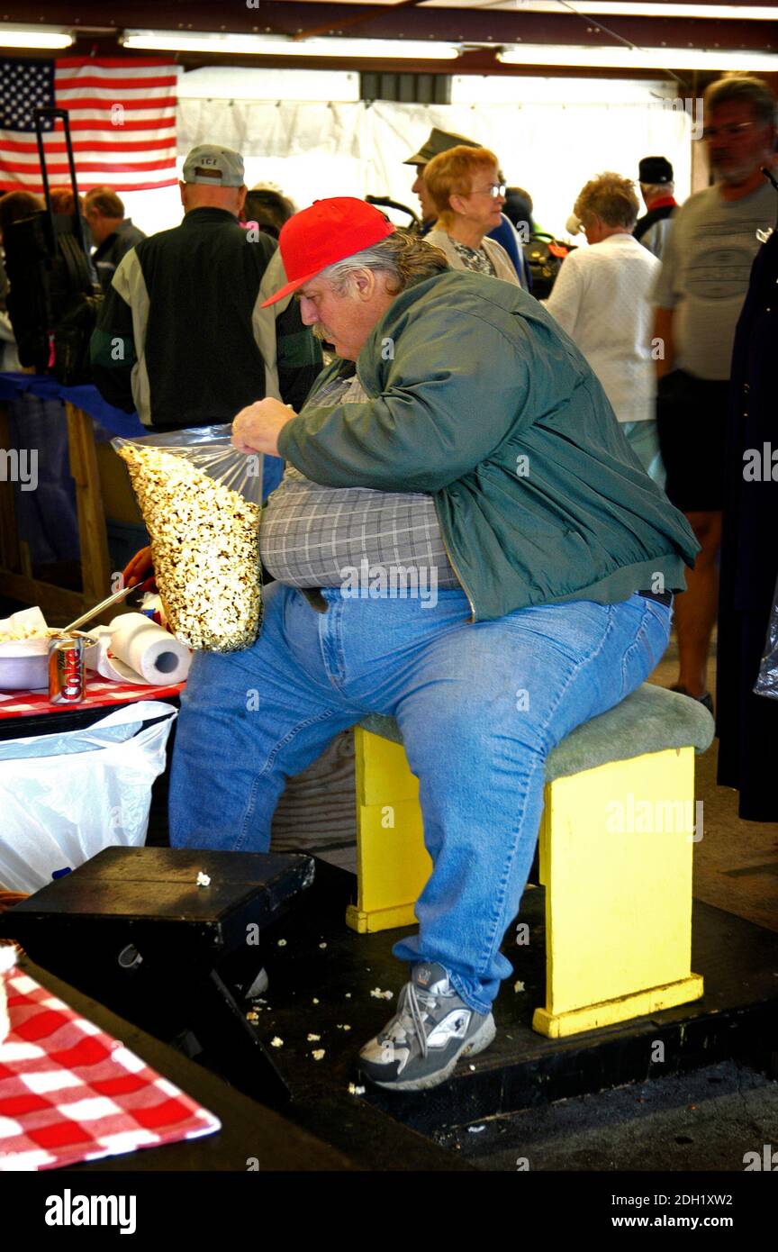 Un homme vraiment gros vendant du pop-corn sur un marché en plein air Banque D'Images
