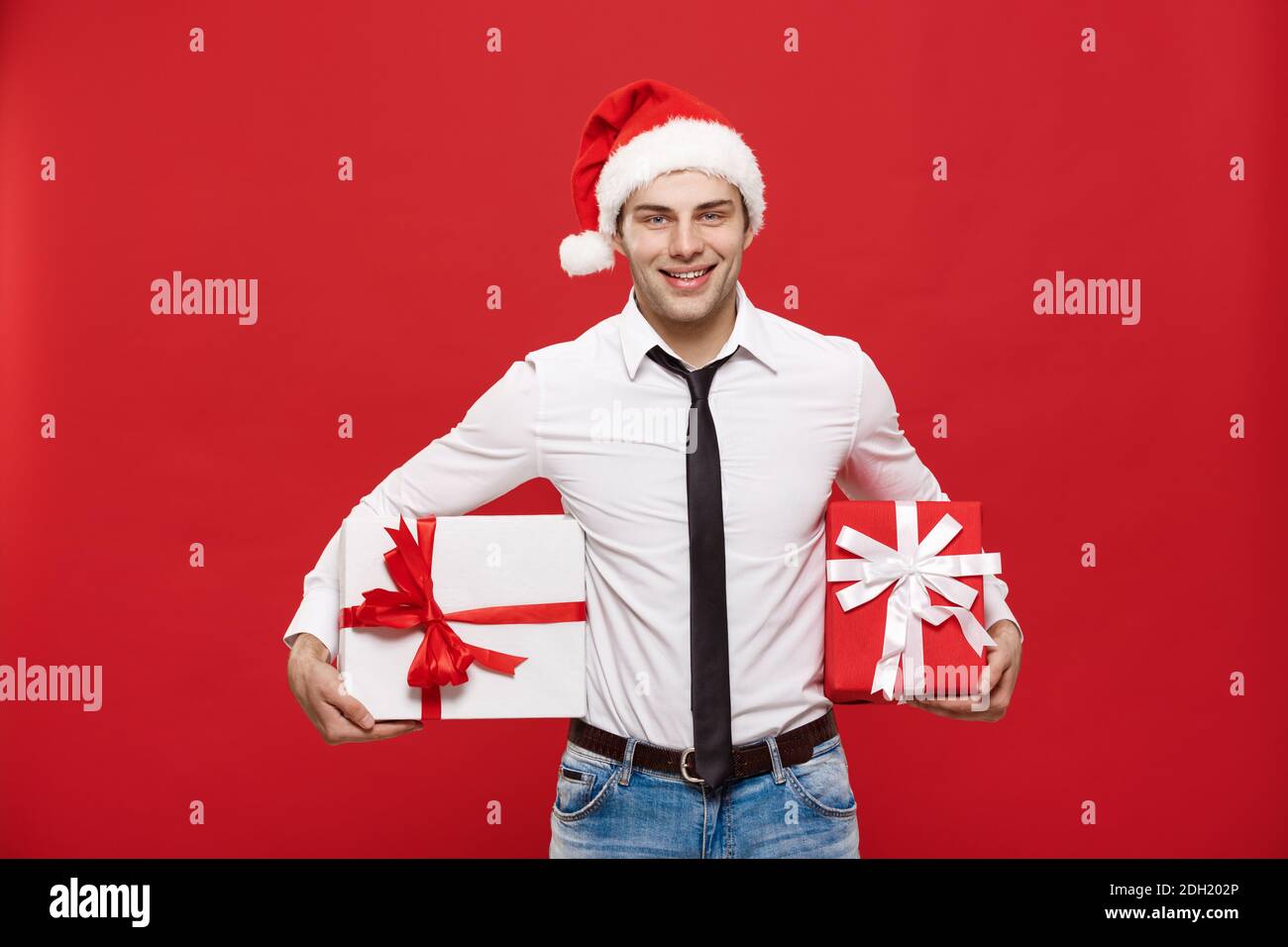 Concept de Noël - portrait heureux homme d'affaires de noël de Noël passionnant avec son cadeau sur fond rouge. Banque D'Images