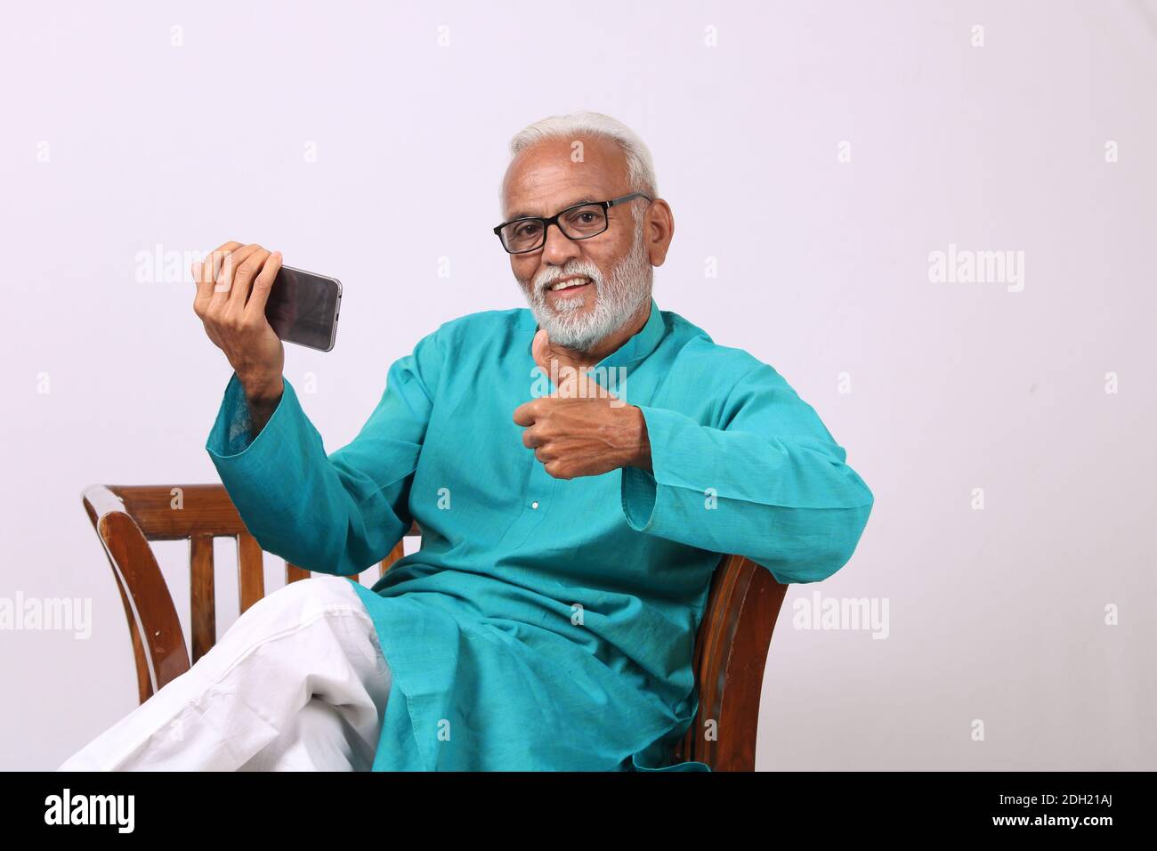 Vieil homme indien à barbe cool utilisant un téléphone portable Banque D'Images