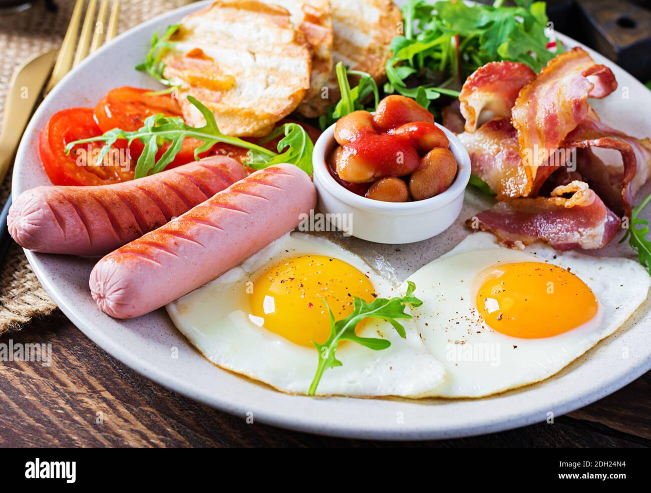 Petit-déjeuner anglais - œufs frits, haricots, tomates, saucisses, bacon et toasts. Banque D'Images