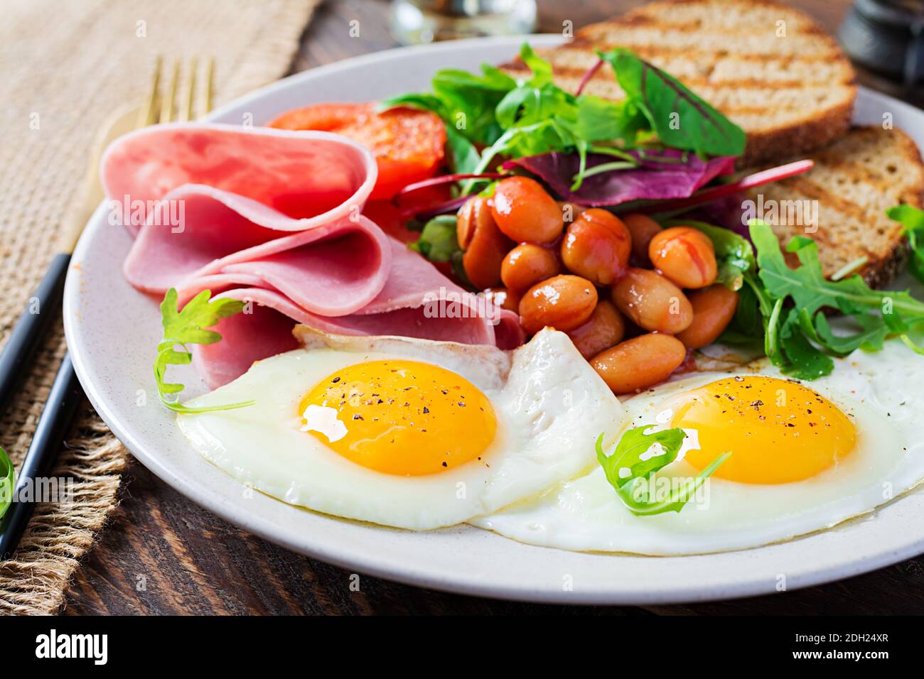 Petit déjeuner anglais - œufs, haricots, tomates, saucisses, jambon et toasts. Banque D'Images