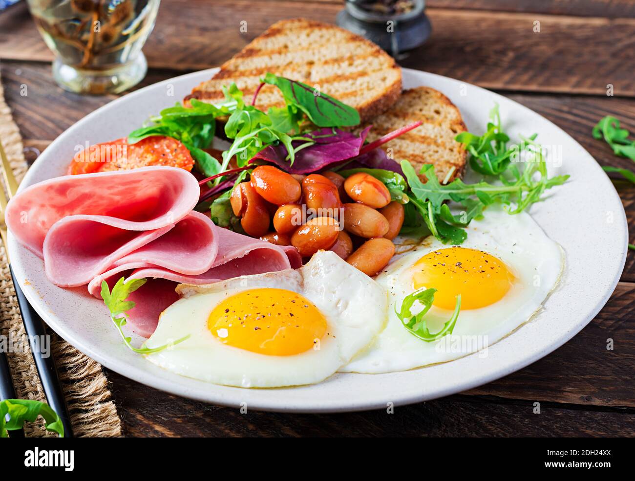 Petit déjeuner anglais - œufs, haricots, tomates, saucisses, jambon et toasts. Banque D'Images