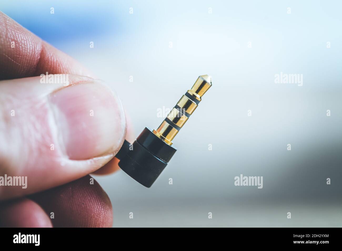 Concept de prise audio : gros plan des doigts mâles tenant une prise audio de 3,5 mm Banque D'Images