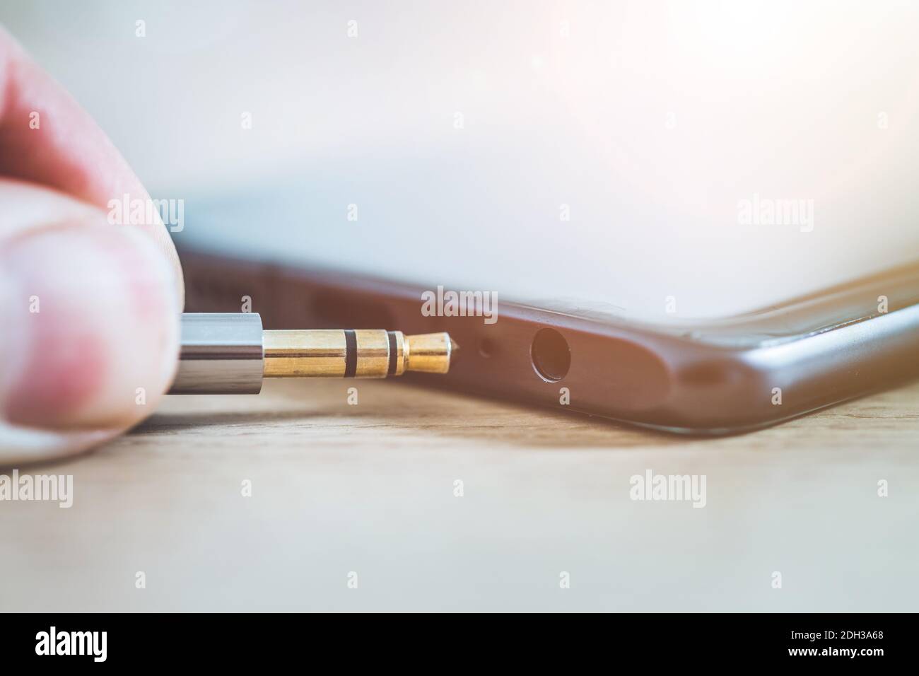 Concept de prise audio : connexion de la prise audio à un téléphone portable noir, gros plan Banque D'Images
