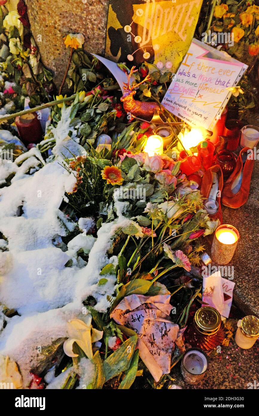 Des fleurs couvertes de neige et de bougies allumées brillent sur le mémorial de fortune David Bowie, à l'extérieur de la Haupstrasse 155 à Berlin, en Allemagne. L'appartement dans le quartier de Schonenberg est où Bowie a vécu à partir de 1976-1979 et où il a créé sa trilogie d'albums. Banque D'Images