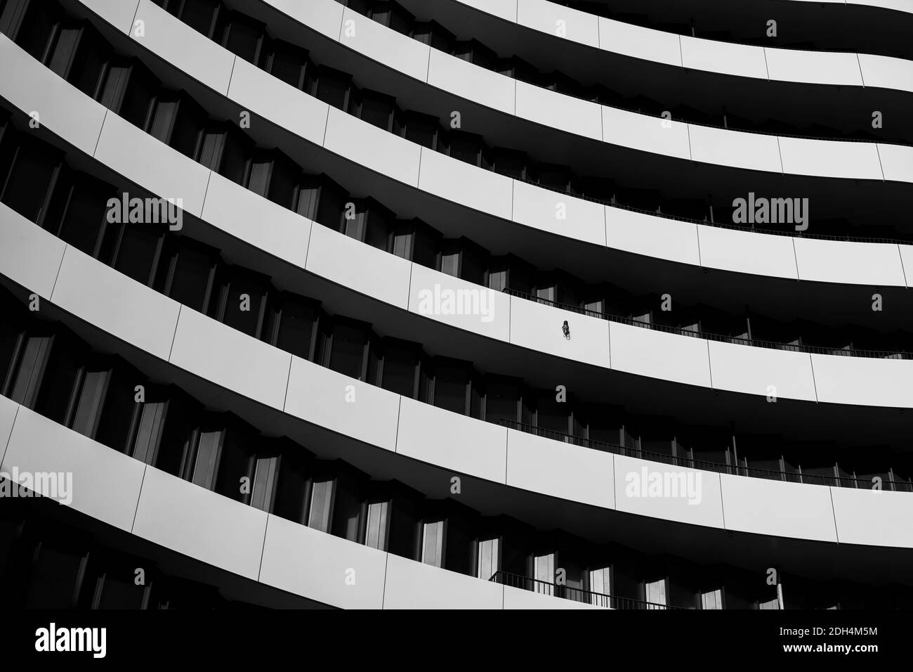 Tons noir et blanc, détail de la façade en courbure extérieure avec des fenêtres noires de couleur contrastée et des panneaux en aluminium blanc en forme ondulée. Banque D'Images