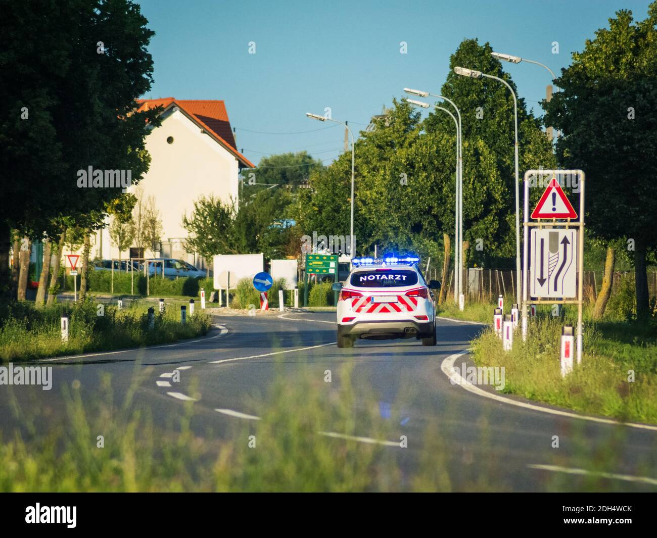 Ambulance avec médecin urgentiste entrant dans un village sur la route Banque D'Images