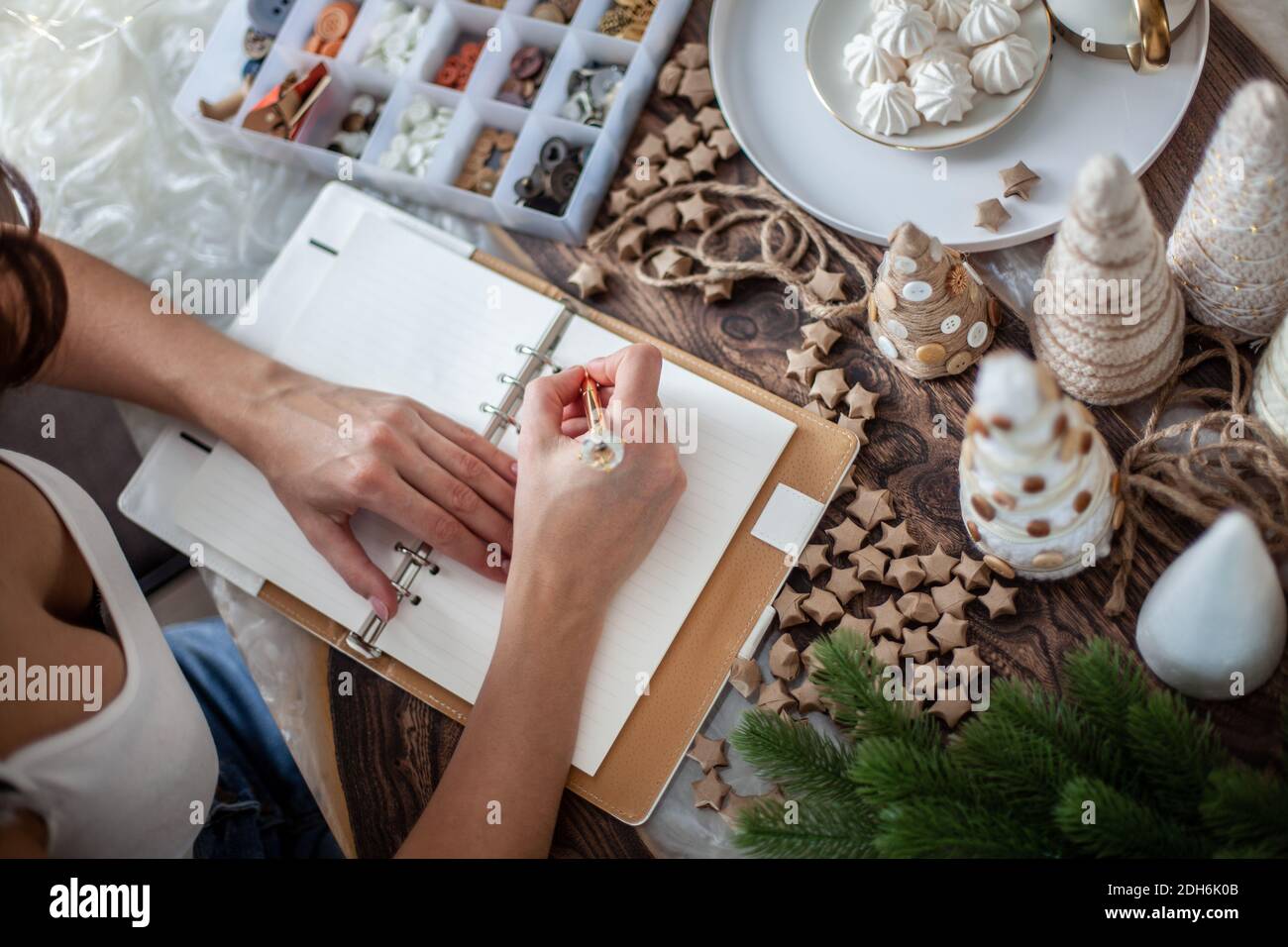 La vue de dessus de la jeune femme écrit des objectifs pour Nouveau Journal de l'année 2021 sur le bureau avec arbre de Noël Banque D'Images