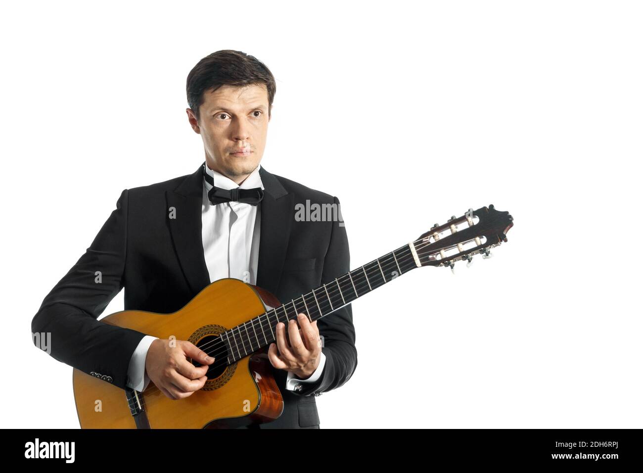 jeune homme en costume classique noir avec noeud papillon posant avec  guitare classique en studio sur fond blanc Photo Stock - Alamy