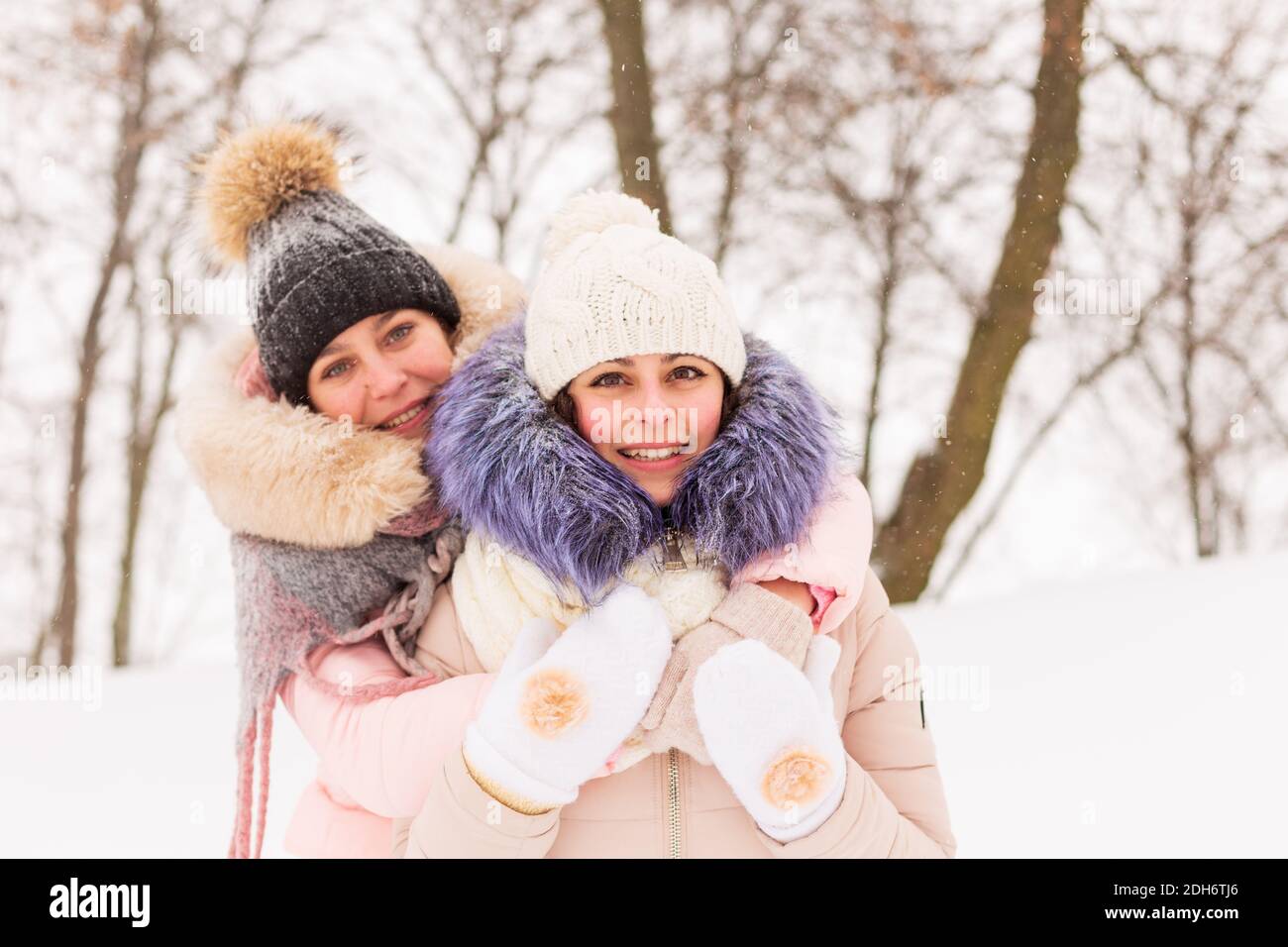 Deux filles marchent dans un parc d'hiver dans la neige. Sœurs sur fond d'arbres enneigés Banque D'Images