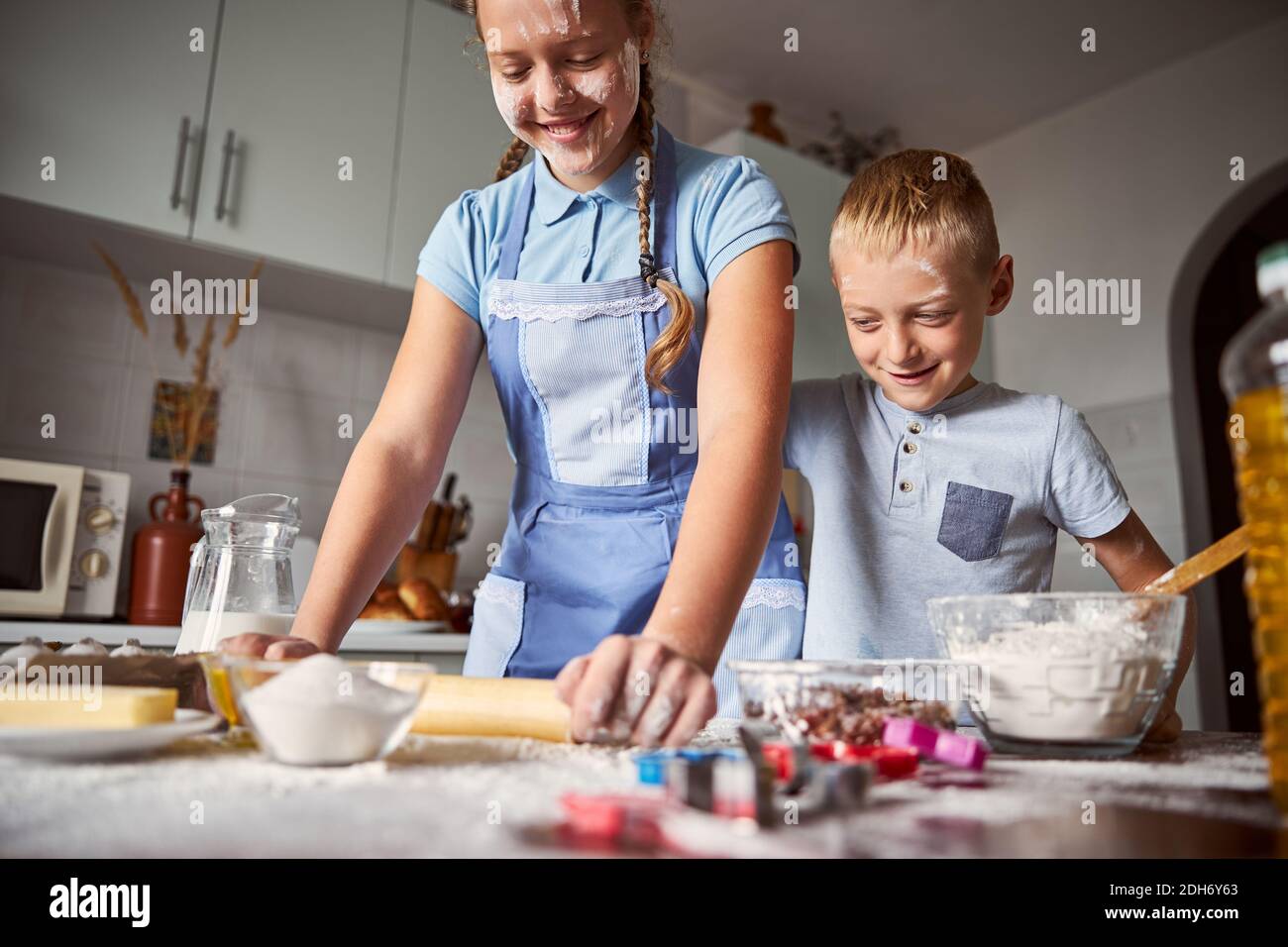 Joyeux jeune fille et garçon préparant la pâte pour la cuisson Banque D'Images