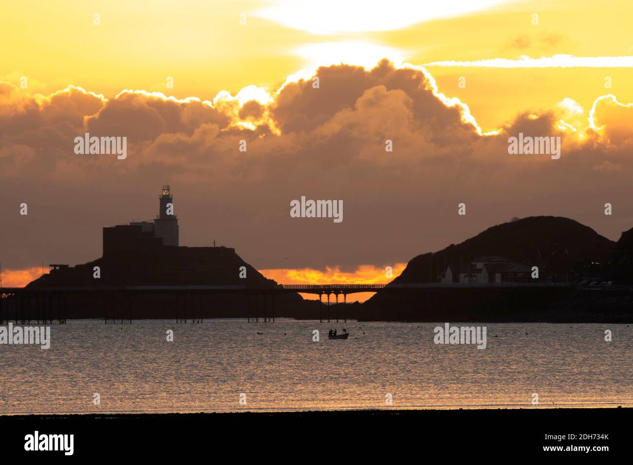 Lever du soleil sur la baie de Mumbles Swansea. Un pêcheur met ses filets Banque D'Images