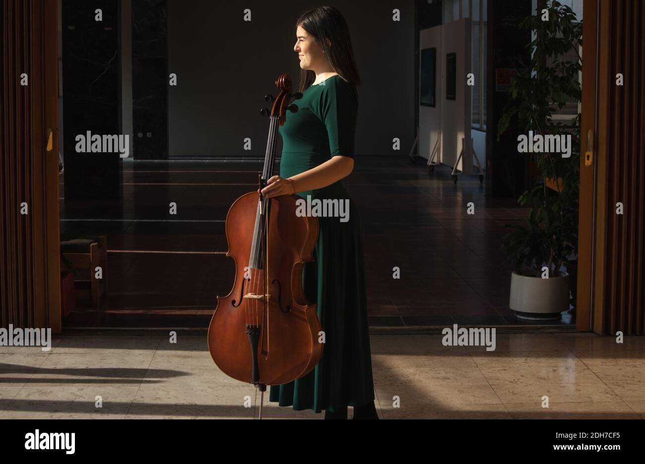 Adolescente avec son violoncelle, posant dans une salle. Banque D'Images