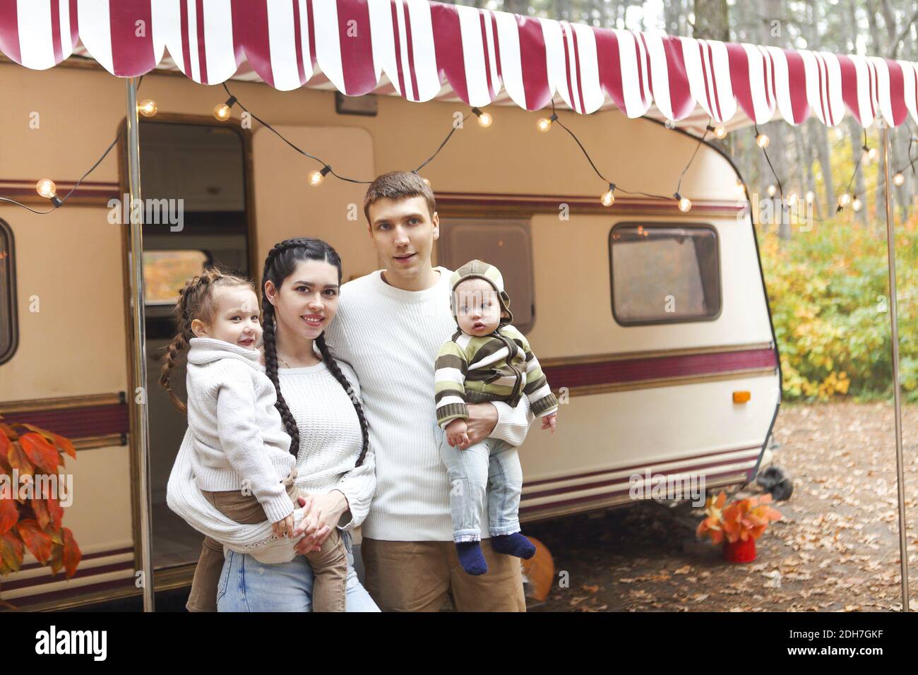 Portrait d'une jeune famille souriante tout en s'embrassant près de la maison sur roues Banque D'Images