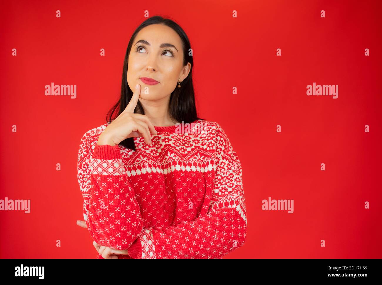 Jeune belle femme portant un chandail décontracté sur fond rouge isolé confusion et se demandant au sujet de la question. Incertain avec doute, pensant avec ha Banque D'Images
