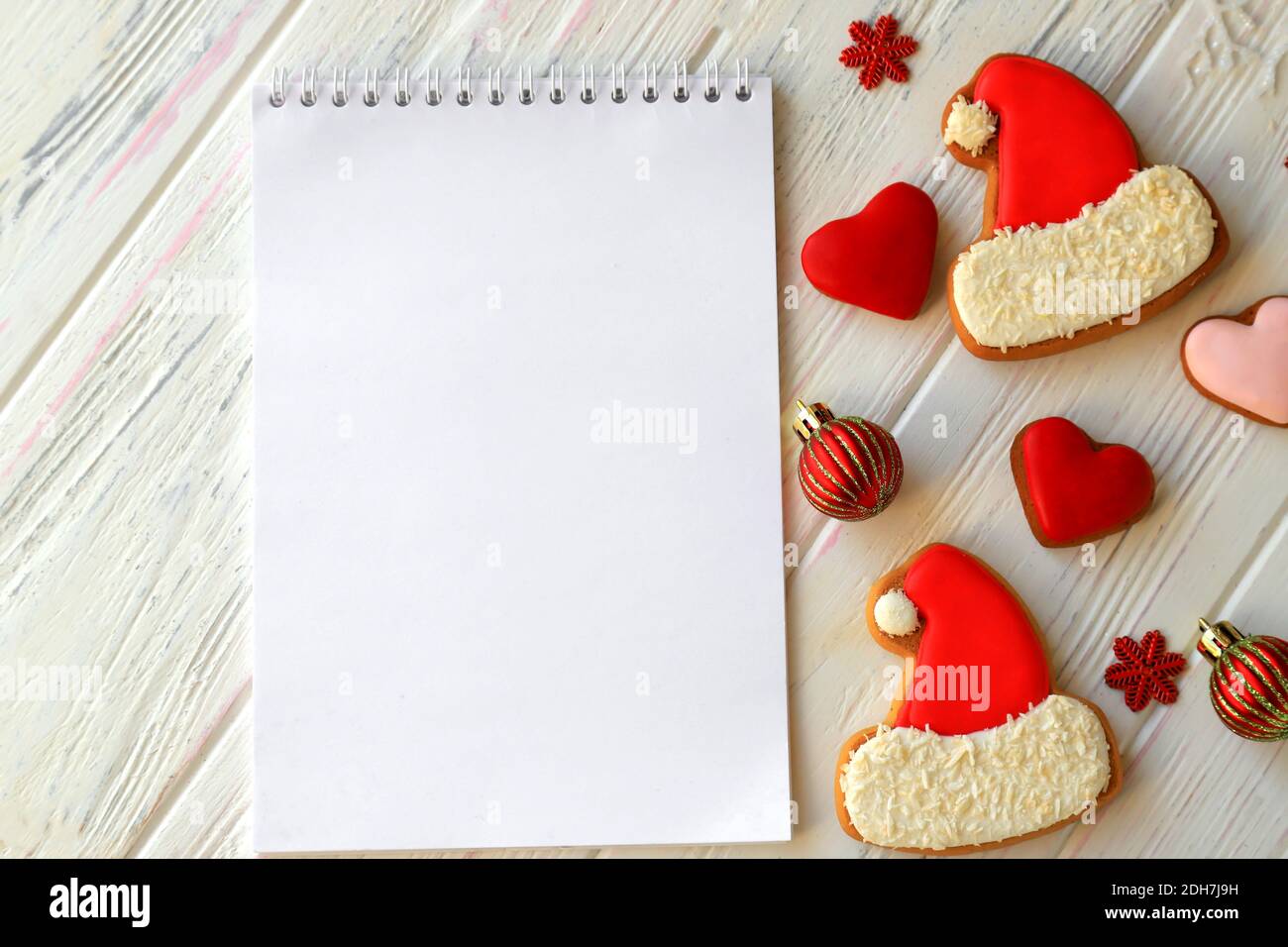 Carnet blanc pour les voeux de Noël, les buts, les tâches, les recettes pour le nouvel an 2021 parmi les biscuits de pain d'épice sous forme de chapeau de Père Noël, les coeurs. Banque D'Images
