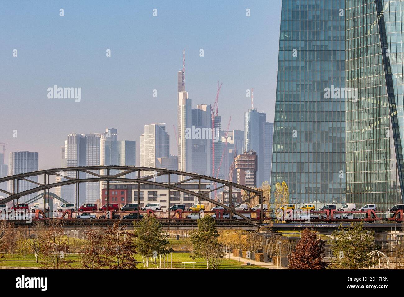 Train de marchandises transportant de nombreuses voitures traversant le pont ferroviaire avec le Frankfurt Skyline en arrière-plan à Francfort-sur-le-main, Hesse, Allemagne. Banque D'Images