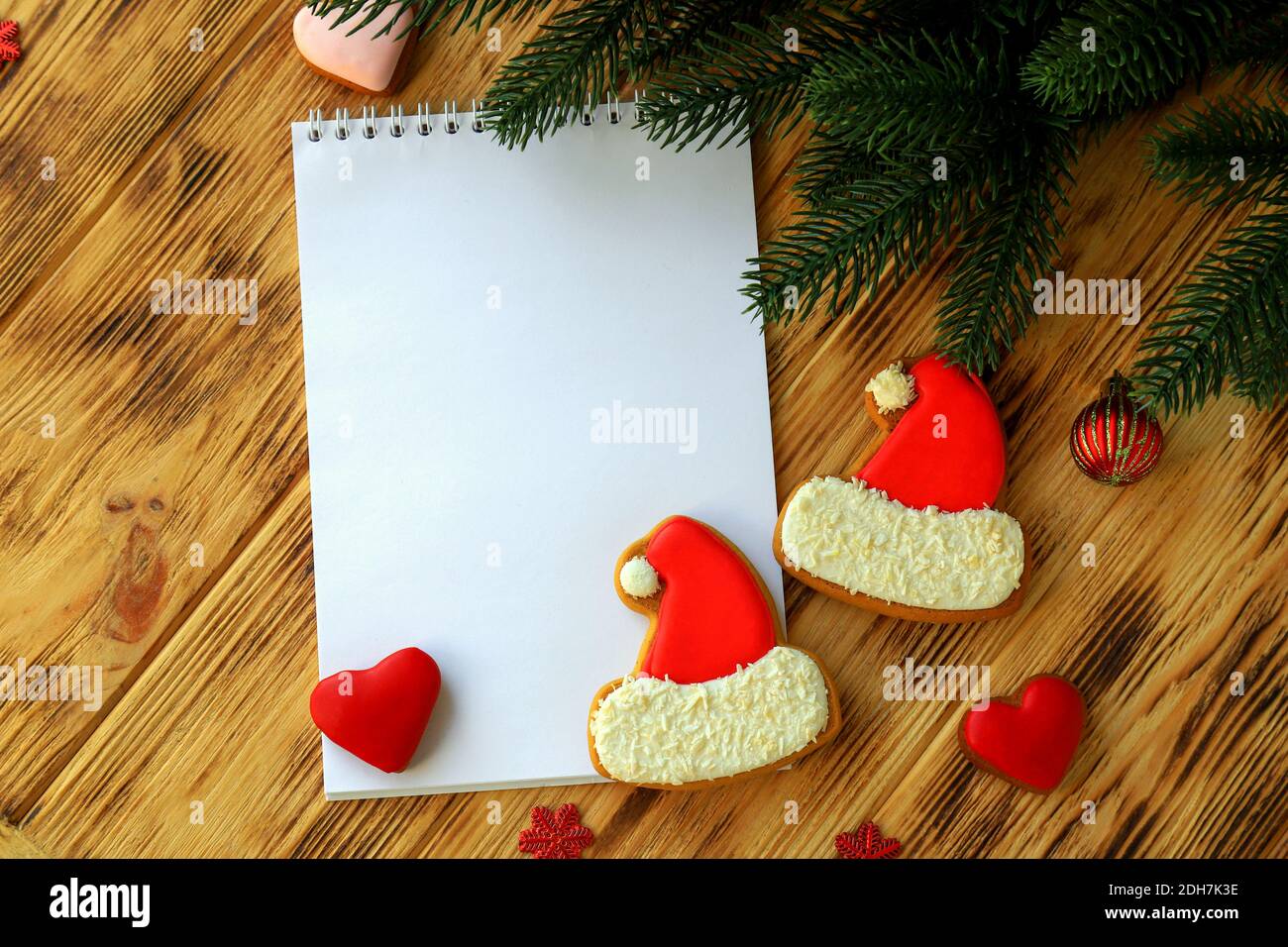Cahier blanc pour les voeux de Noël, les buts, les tâches, les recettes pour le nouvel an 2021, les biscuits de pain d'épice sous forme de chapeau de Père Noël, les coeurs. Noël Banque D'Images