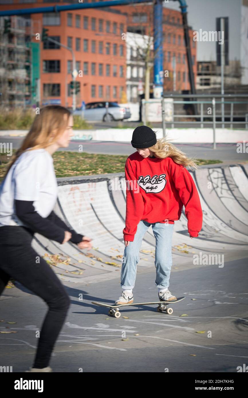 Deux filles patineuses sur rampe en béton .boxeurs femelles en tenue décontractée s'amuser au Skatepark. La sous-culture urbaine et le skateboard comme style de vie. Banque D'Images