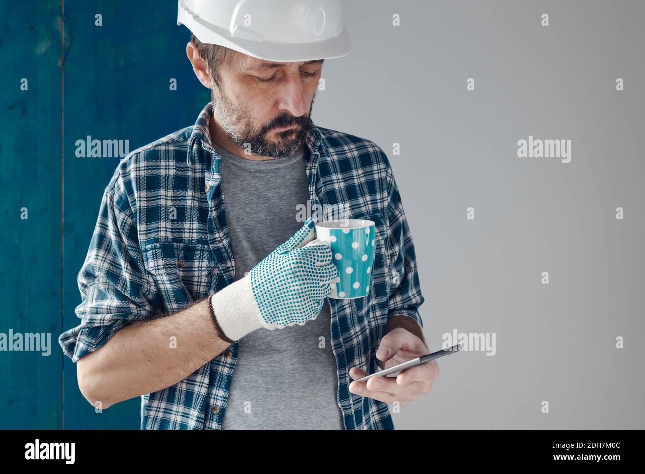 Ingénieur de construction sur une pause-café matinale à l'aide d'un téléphone portable, se détendre et se préparer au travail Banque D'Images