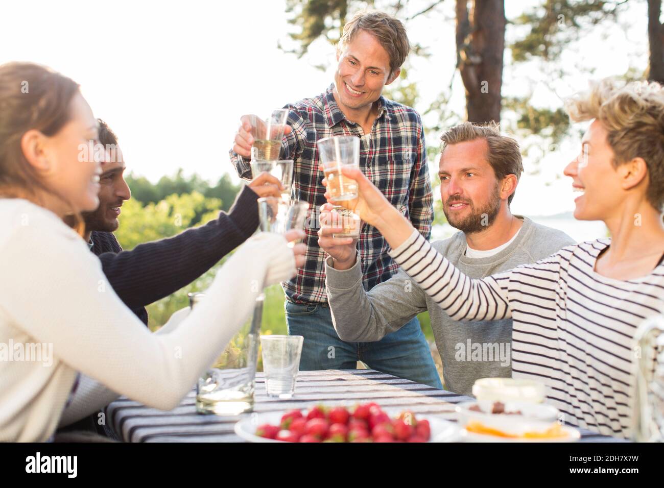Groupe d'amis heureux de griller des verres de bière pendant le déjeuner à table de pique-nique Banque D'Images