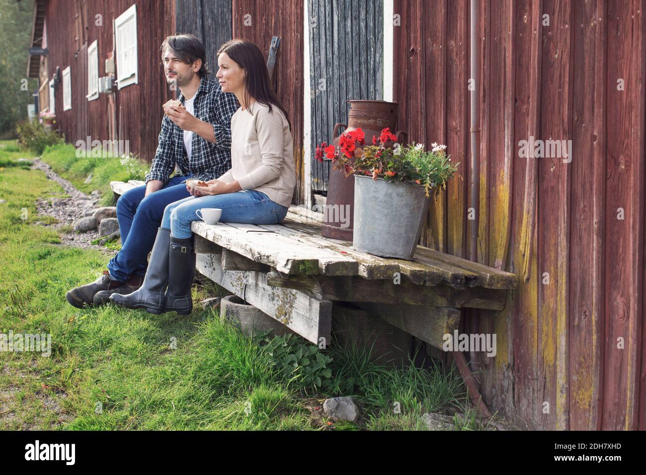 Couple prenant le petit déjeuner tout en étant assis à l'extérieur de la grange à la ferme Banque D'Images