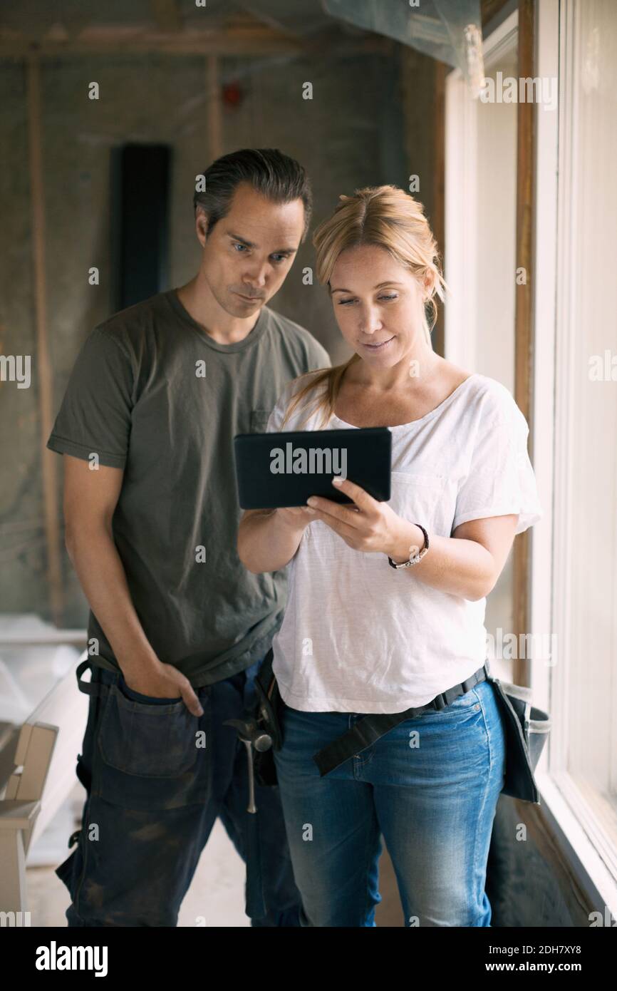 Couple utilisant une tablette numérique dans la maison en cours de rénovation Banque D'Images