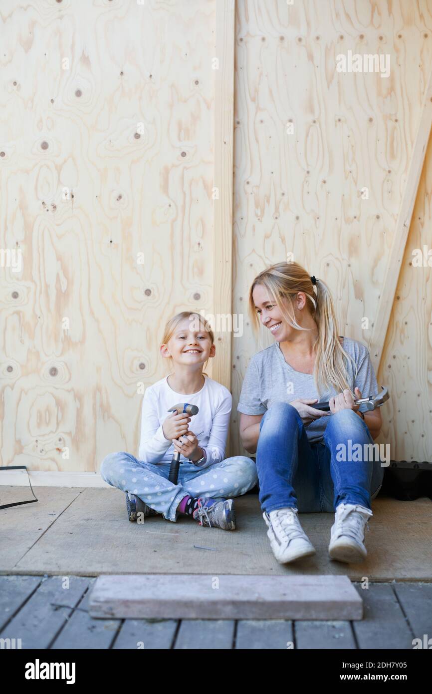 Bonne mère et fille tenant des marteaux contre le mur de la maison en cours de rénovation Banque D'Images