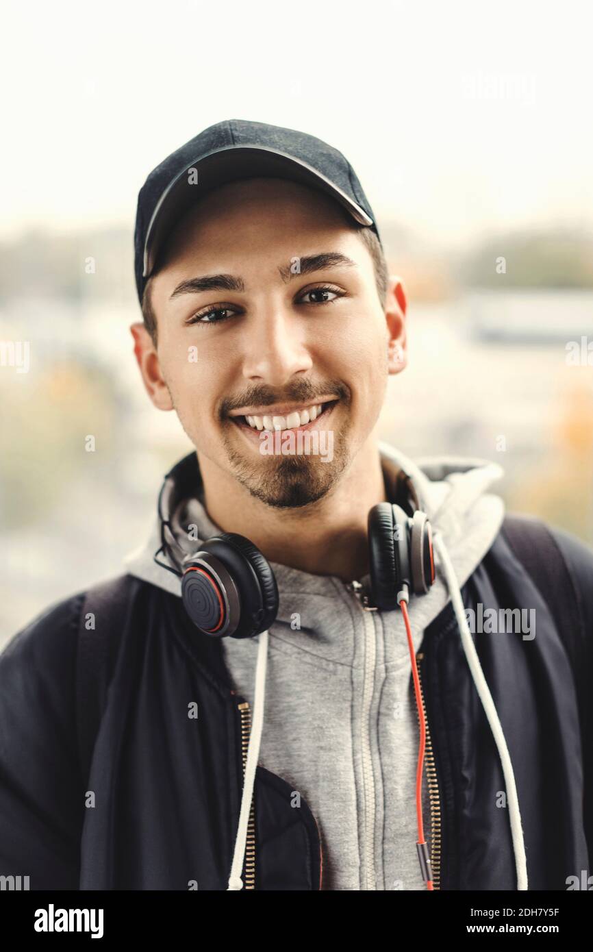 Portrait d'un étudiant universitaire heureux avec un casque autour du cou à l'extérieur Banque D'Images