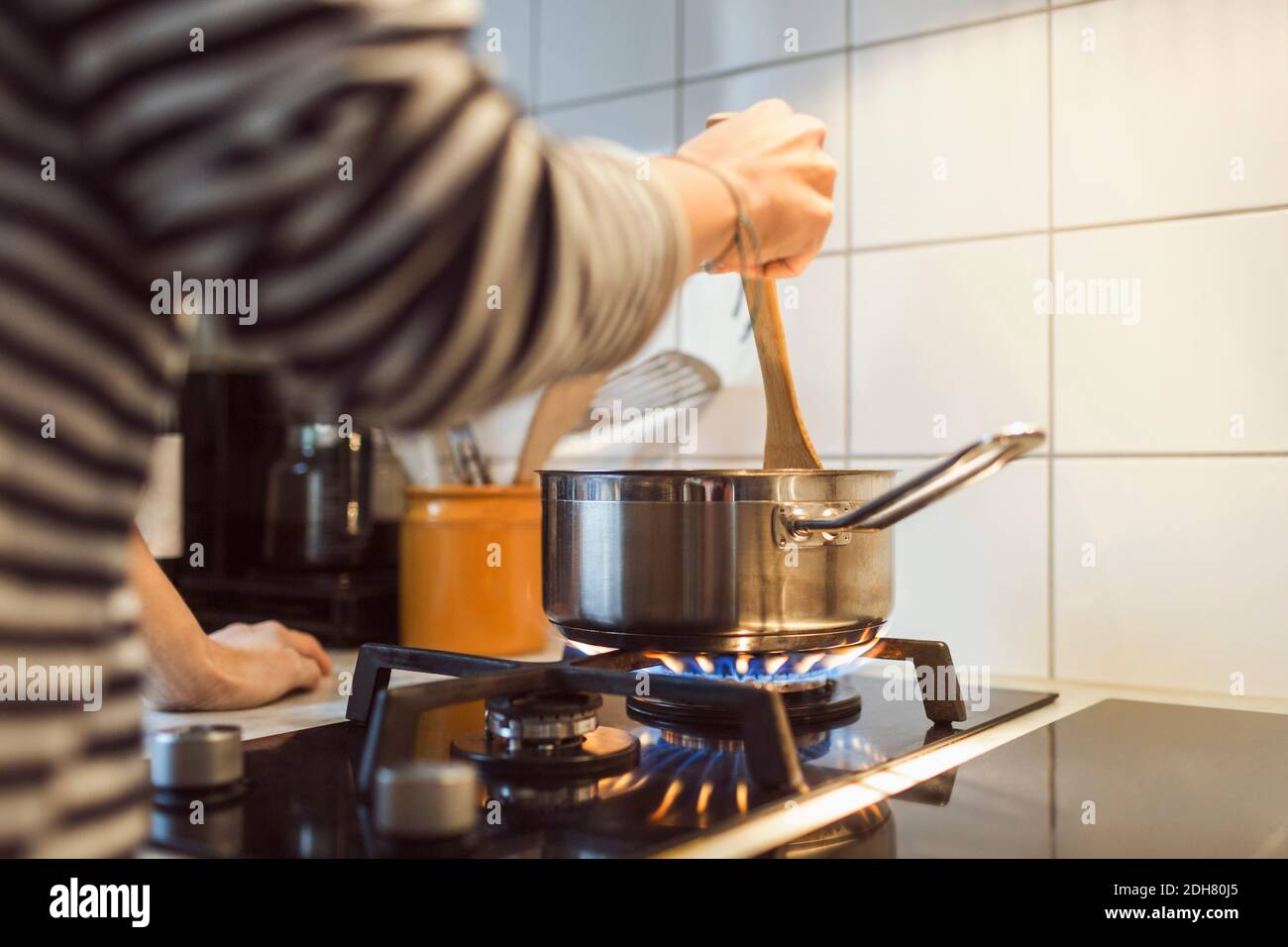 Image rognée de la femme tenant la spatule dans la casserole pendant cuisine sur cuisinière Banque D'Images