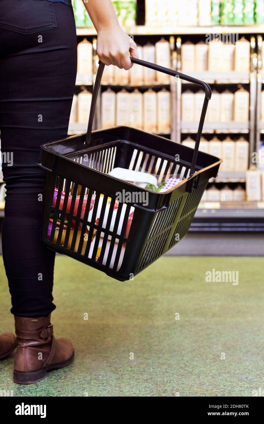 Section basse de la femme portant le panier dans le supermarché Banque D'Images
