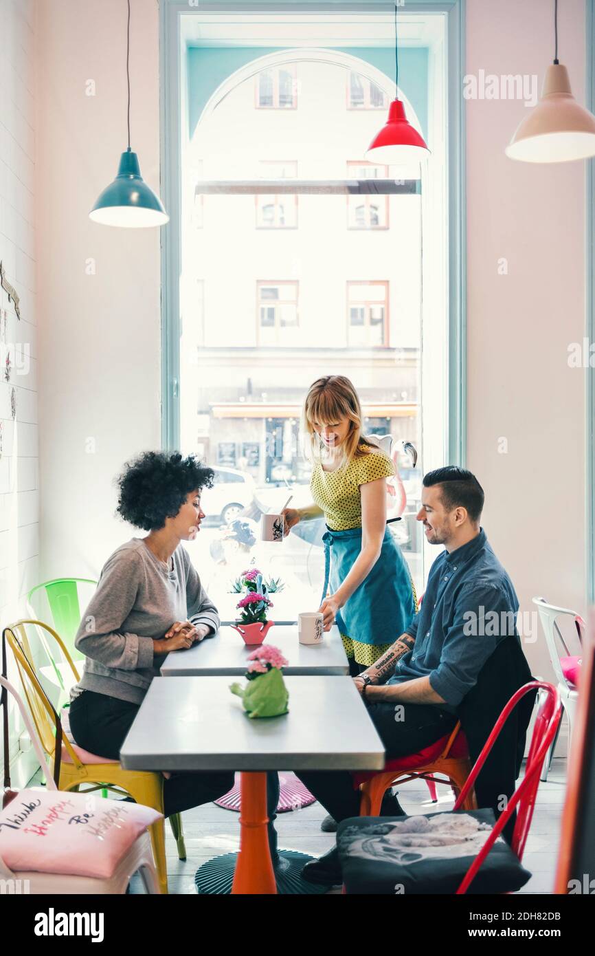 Serveuse servant du café aux clients dans le café-restaurant Banque D'Images