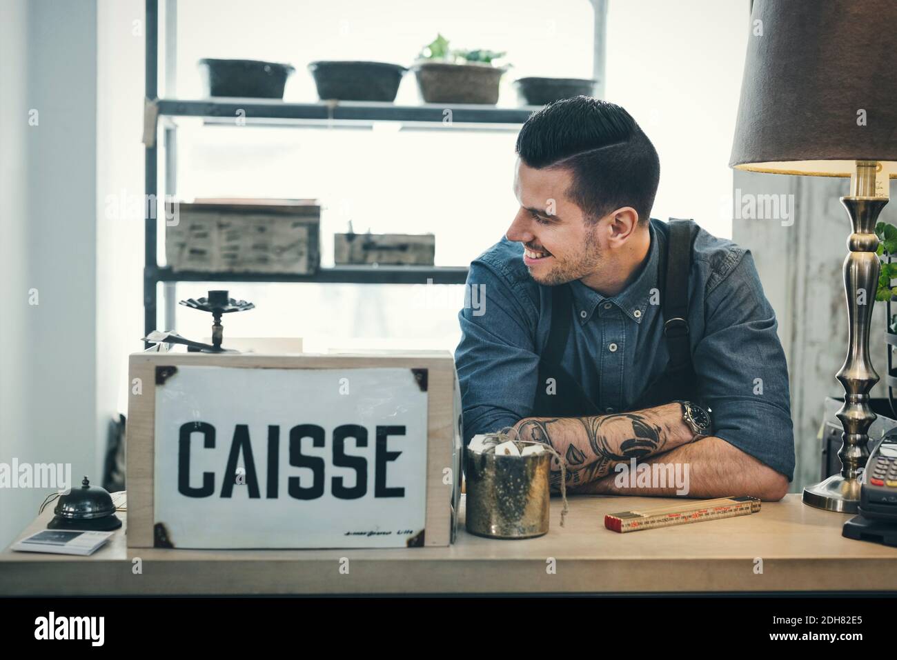 Un caissier souriant regarde loin du comptoir-caisse Banque D'Images