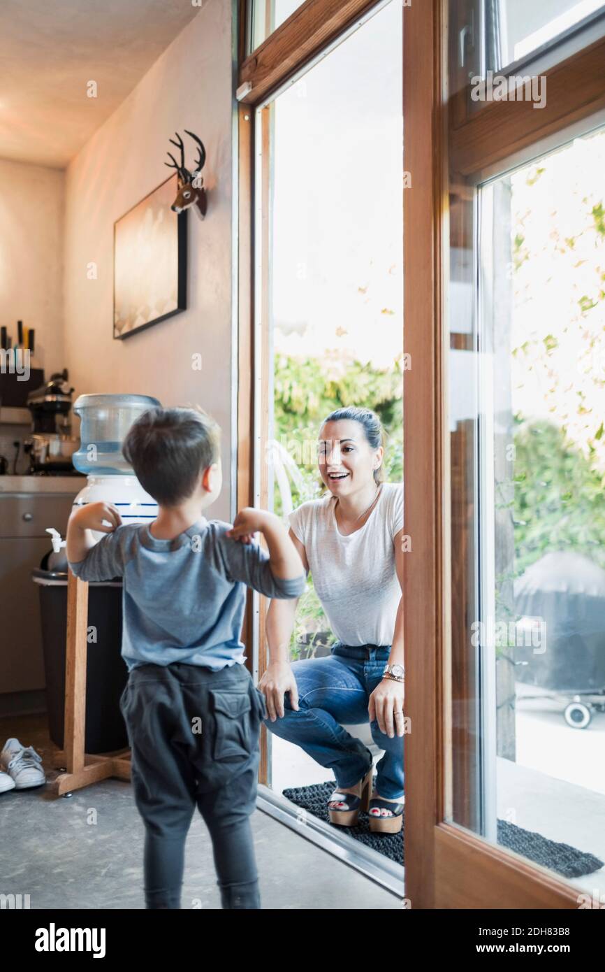 Bonne femme regardant son fils en se croquant sur la porte Banque D'Images