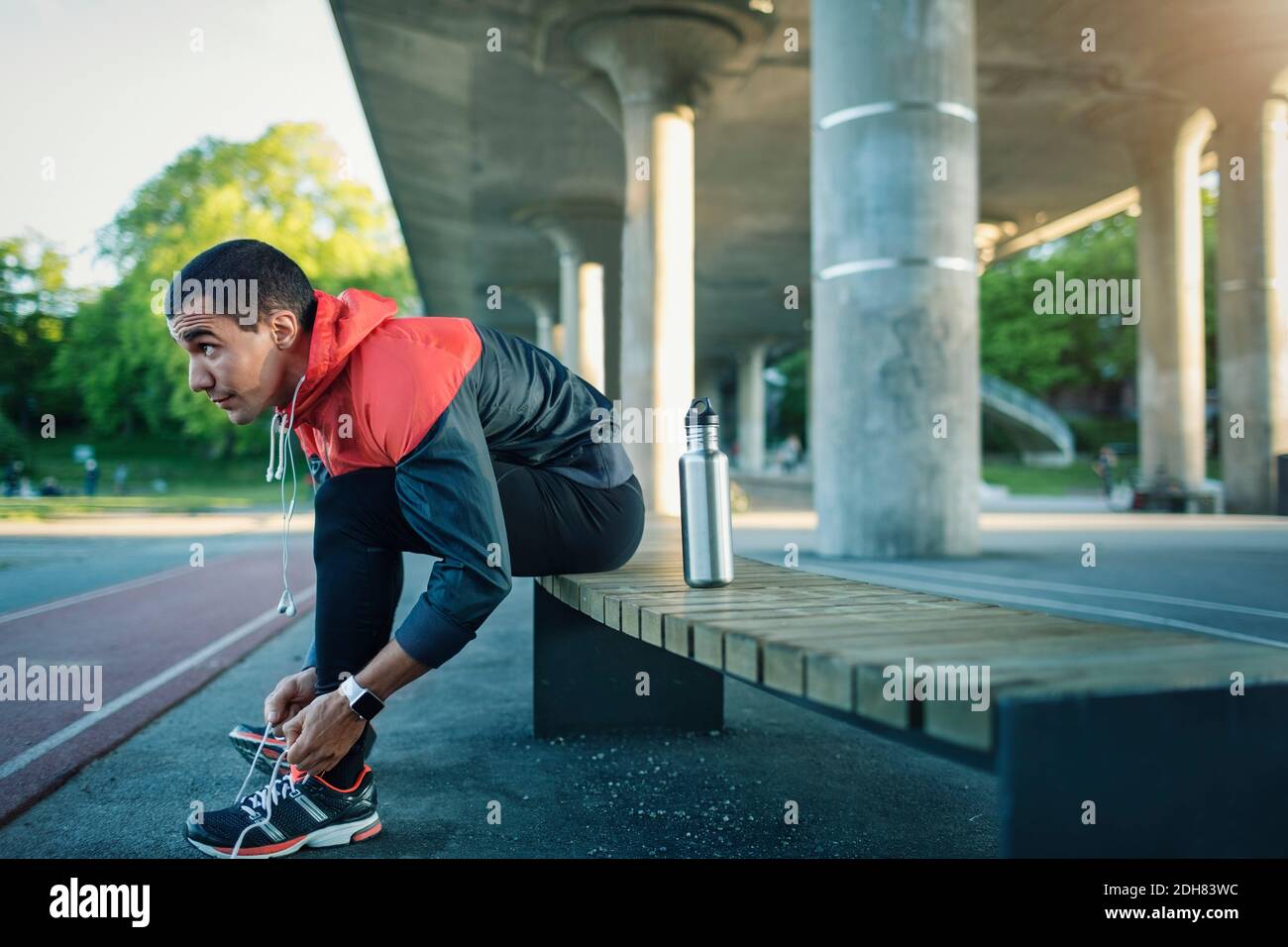 Homme attachant une cordonnet assis sur un banc Banque D'Images