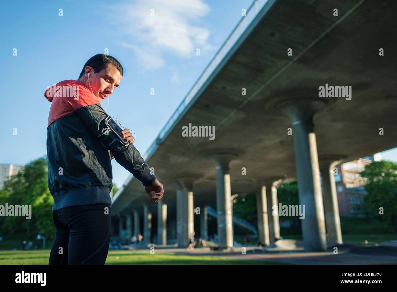 Vue à angle bas de l'homme qui touche le bracelet du bras en position debout contre le pont Banque D'Images